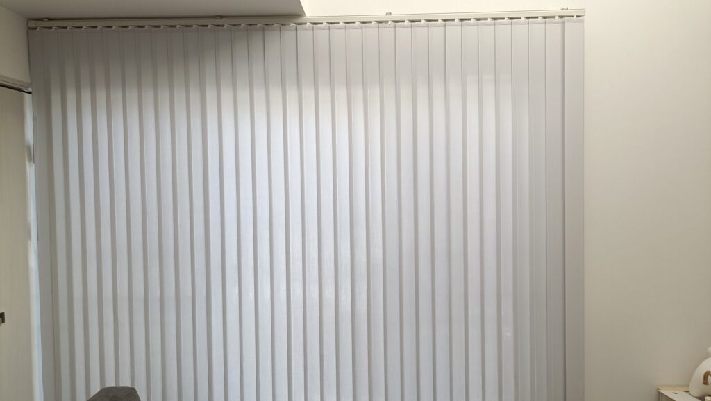 東側の三枚窓に設置したバーチカルブラインド。縦ラインがリビングをすっきり見せ、光の向きを調整して柔らかな明るさを演出している。