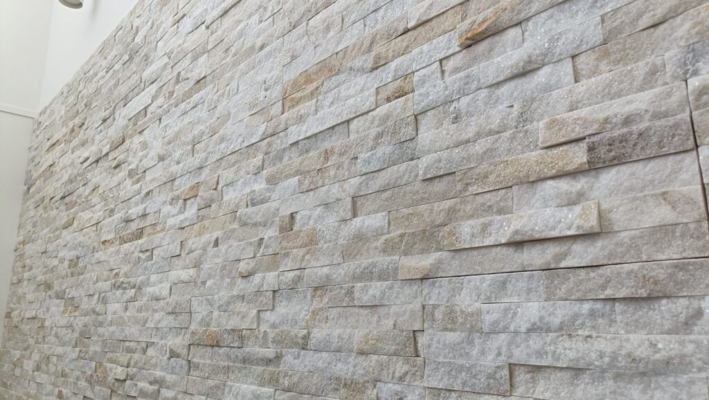 一条工務店グランスマートのリビングに採用したバンピーウォールを斜めから撮影。天然石の立体的な凹凸と陰影が際立ち、光の角度で表情が変わる。